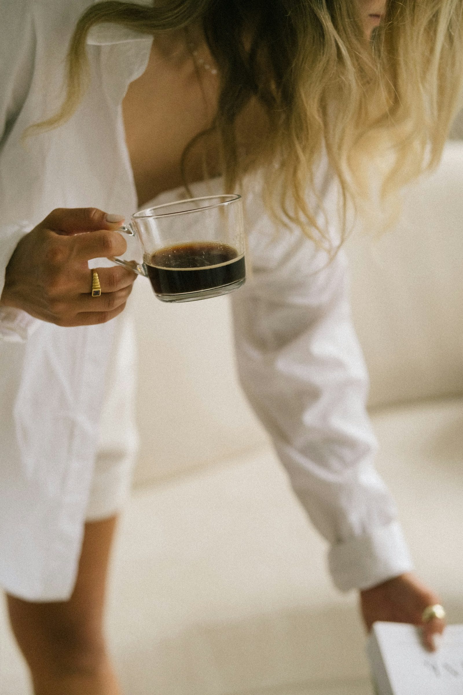 Hand holding a cup of coffee in a bright, relaxed setting
