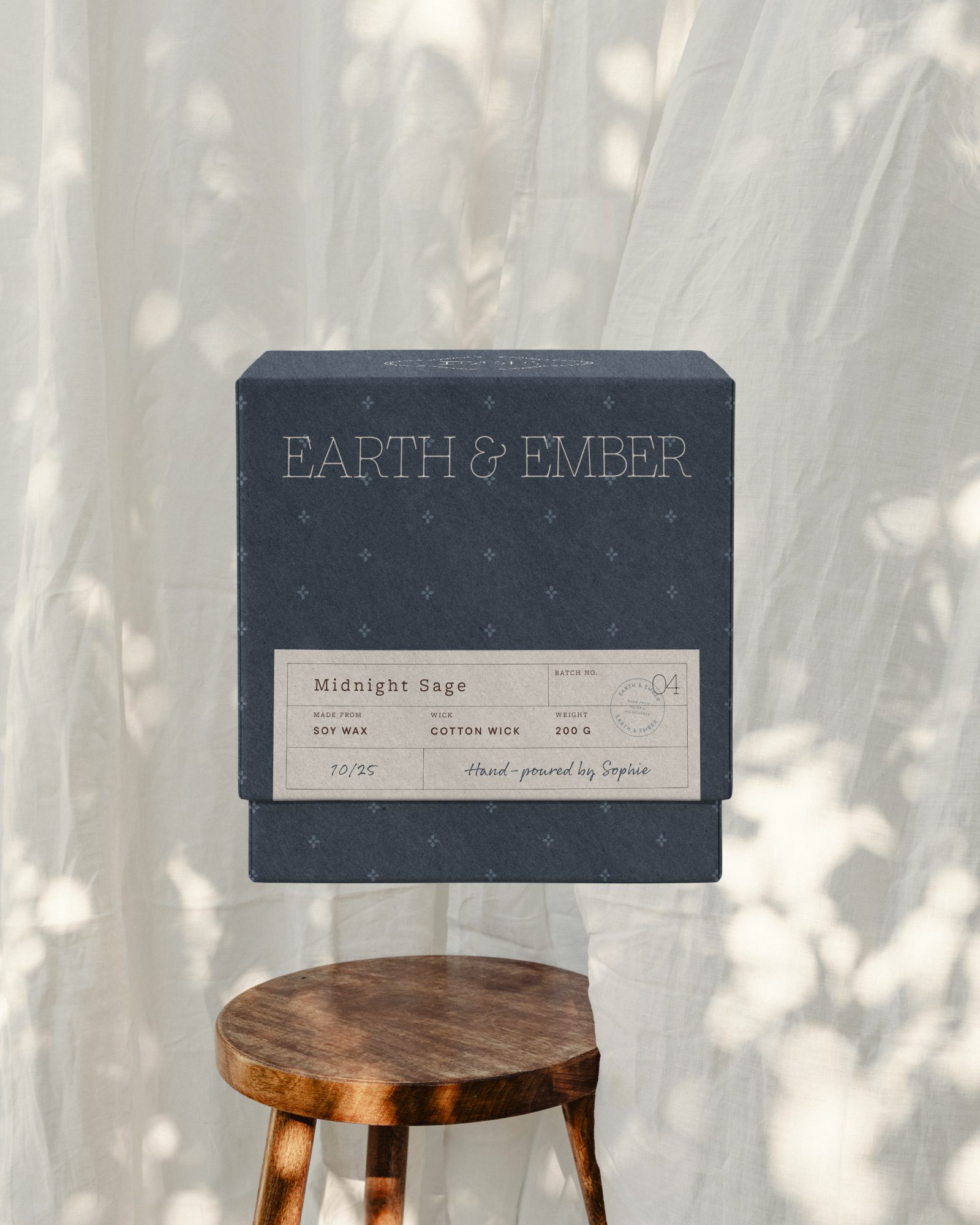 Earth & Ember Midnight Sage candle box on soft fabric background